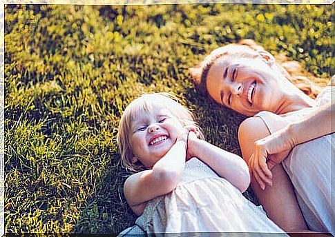 Mother laughing with her daughter in the grass, because she is not a bad mother