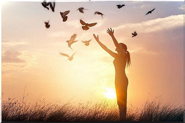 Woman releasing birds at sunset