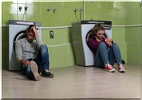 A couple is sitting against washing machines