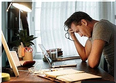 A tired man is sitting at his desk