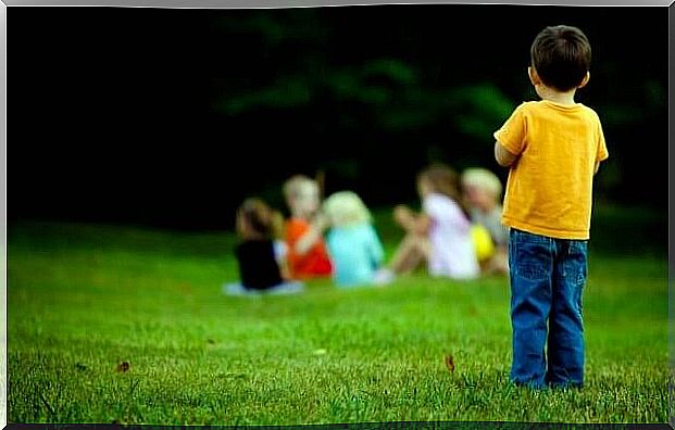 Little Boy Standing Alone Looking At A Group Of Children Ahead As An Example Of How Children Suffering From Asperger's Syndrome Are